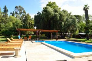 a swimming pool with chairs and a wooden pergola at Posada Los Cipreses in San Rafael