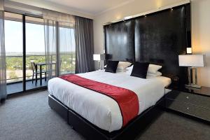 a bedroom with a large bed with a large window at Rydges Palmerston - Darwin in Darwin