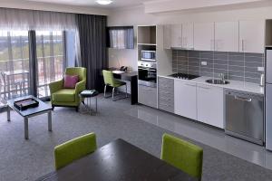 
a kitchen with a table, chairs and a refrigerator at Rydges Palmerston - Darwin in Darwin
