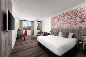 a hotel room with a bed and a brick wall at Rydges Sydney Central in Sydney
