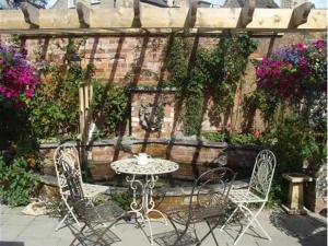 un patio con mesa, sillas y flores en The Old Brewhouse, en Cirencester