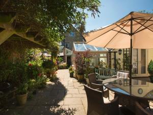 eine Terrasse mit einem Tisch, Stühlen und einem Sonnenschirm in der Unterkunft The Old Brewhouse in Cirencester