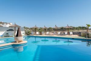 a swimming pool with umbrellas and chairs and a swimming pool at Orange Colom - Seaside Apartments in Portocolom