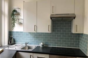 a kitchen with a sink and a blue tiled wall at Stylish studio gem in the heart of Hebden in Hebden Bridge