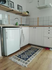 a kitchen with white cabinets and a rug on the floor at Apartament ZatokaPuck in Puck