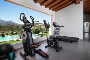 a fitness room with two exercise bikes and a window at Hotel San Teodoro in San Teodoro