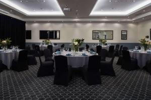 una sala de conferencias con mesas y sillas en una habitación en Rydges Norwest Sydney, en Baulkham Hills