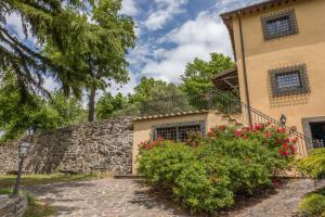 a house with a stone wall and red flowers at Casale Eclissi in Bagnaia