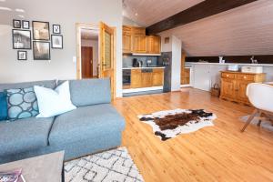 a living room with a blue couch and a kitchen at Sylvies Alpenglück- Zentral- für 4 in Oberstaufen +6 photos