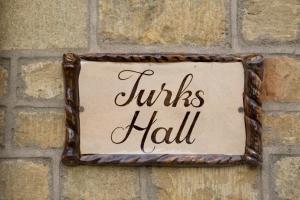 una señal que lee el pasillo de las tortugas colgando de una pared de ladrillo en Turks Hall en Bruton