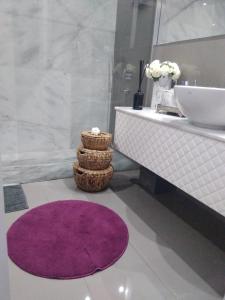 La salle de bains est pourvue d'un tapis violet et d'un lavabo. dans l'établissement Luxury 3 Bedroom Penthouse With Private Garage, à Braga