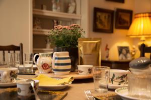 a table with plates and cups and a vase with flowers at Turks Hall in Bruton