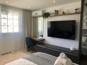 a bedroom with a large flat screen tv on a wall at Flat Garden Itaipava in Itaipava