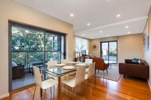 a dining room and living room with a glass table and chairs at 2 Bdrm North Sydney with stunning harbour views - 16WAL in Sydney