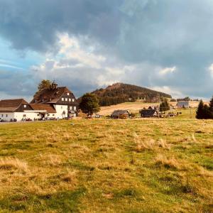 ein Grasfeld mit Häusern im Hintergrund in der Unterkunft Panský dům - Jizerka in Jizerka