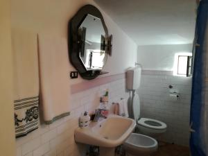 ein Badezimmer mit einem Waschbecken, einem WC und einem Spiegel in der Unterkunft Casa "Albero Verde" in Raffo