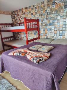 a bed with a purple blanket and pillows on it at Pousada Bela Vista Maricá in Maricá