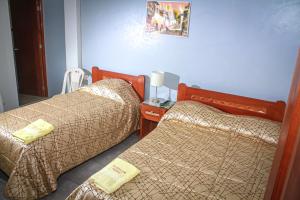 Habitación con 2 camas y mesa con lámpara. en Hotel Virgen del Carmen - Huaraz, en Huaraz