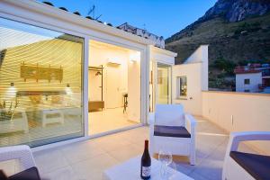patio z białymi krzesłami i stołem z butelką wina w obiekcie Porta del Golfo Apartments & Suites w mieście Castellammare del Golfo