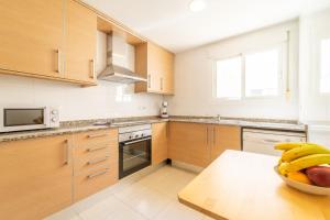 una cocina con armarios de madera y un bol de fruta en una mesa en MyFlats Luxury Navas, en Alicante