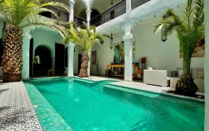 a large swimming pool with palm trees in a room at Riad Fabiola Et Spa in Marrakesh