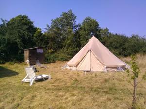 una tienda y una silla en un campo en Yourte et tente dans un écolieu avec piscine hors-sol, en Péault