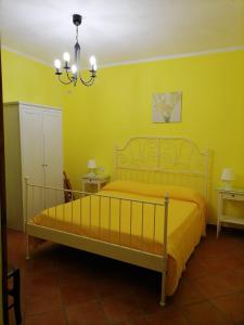 een slaapkamer met een bed met gele muren en een kroonluchter bij La Vecchia Casa in San Mauro Cilento