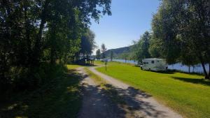 a dirt road next to a river with an rv parked at Värnäs Camping in Stöllet