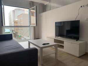 sala de estar con TV de pantalla plana y mesa en Oxford Suites Ciudad de la Coruña en A Coruña