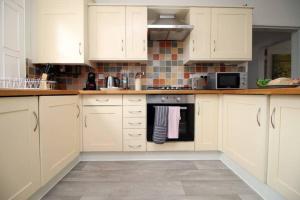 a kitchen with white cabinets and a stove top oven at Spacious Georgian 3bedroom Apartment, 5 mins from Bath Abbey in Bath