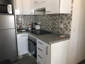 a kitchen with white cabinets and a sink and a refrigerator at Guadalajara apartamento in Torrevieja