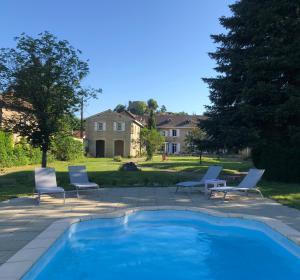 a swimming pool with chairs and a house in the background at Le Clos Ayanna in Crémieu