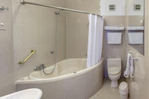 a bathroom with a tub, toilet, sink and shower at Miraflores Colon Hotel in Lima