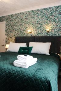 a green bed with a pile of towels on it at Cambridge House room only accommodation for Adults in Windermere