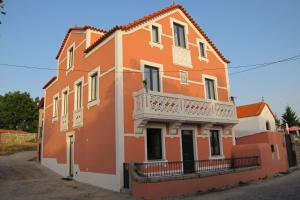an orange building with a balcony on a street at Villa Tauria- Casa de campo em aldeia medieval in Sabugal