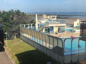 a building with a swimming pool next to a beach at Le 84 in Courseulles-sur-Mer