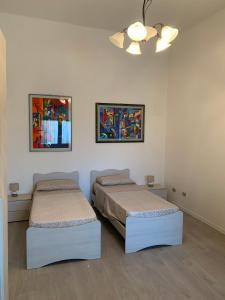 two beds in a room with two paintings on the wall at Casa San Paolo in Sarnico