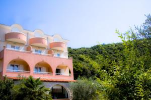 różowy budynek z balkonem na górze w obiekcie Hotel Carmen w mieście Krnica