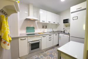 Una cocina con gabinetes blancos y un horno de estufa. en Cuencaloft Calderón de la Barca, en Cuenca