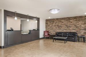 une salle d'attente avec des meubles en cuir et un mur en briques dans l'établissement Red Roof Inn & Suites Lake Charles, à Lake Charles