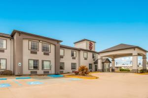 a large tan building with a clock tower at Red Roof Inn & Suites Lake Charles in Lake Charles