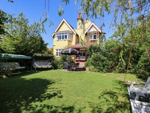 a house with a lawn in front of it at Yellow House on the Corner in Frinton-on-Sea