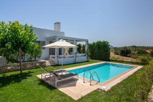 a villa with a swimming pool and an umbrella at Sofia Luxury Villas in Panormos Rethymno