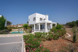 a white house with a garden and a swimming pool at Sofia Luxury Villas in Panormos Rethymno