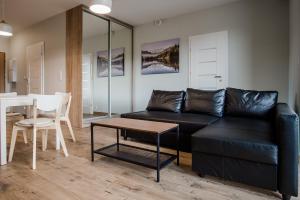 a living room with a black couch and a table at Shipyard Gdańsk Apartment - free private parking in Gdańsk