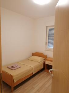 een kleine slaapkamer met een bed en een raam bij Salona Croatia in Solin