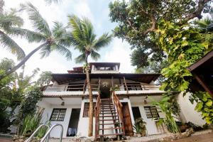 a white house with a staircase and palm trees at Pousada Villa di Milos - By Quarto à Vista in Pipa