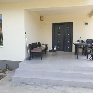 eine Terrasse mit Tischen und Stühlen und einer schwarzen Tür in der Unterkunft Casa Margareta in Eforie Sud