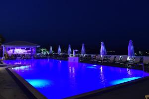 ein Swimmingpool bei Nacht mit blauen und violetten Lichtern in der Unterkunft King Minos Hotel in Tolo