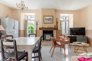 uma sala de estar com uma mesa e uma lareira em Maison avec beau jardin - Centre ville d'Arromanches em Arromanches-les-Bains